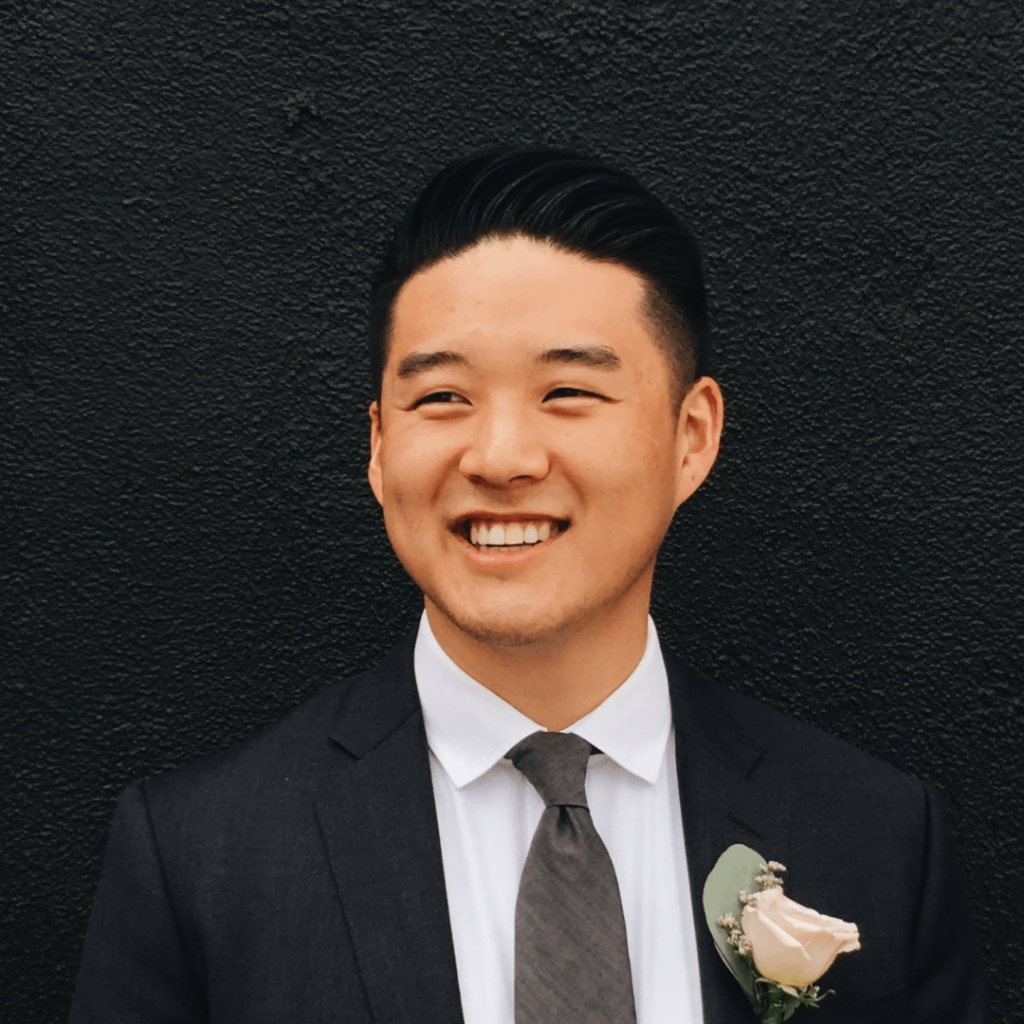 Headshot of Simon Park, a web developer at HustleFish, wearing a snazzy black suit with a white shirt and white rose boutonniere